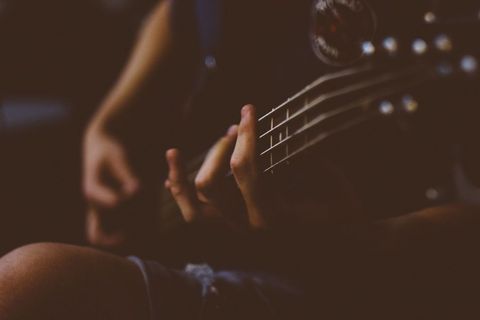 Focus on Hand Playing Acoustic Guitar in Dim Light