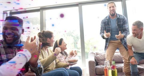 Cheering friends with confetti, snacks and bottles in bright living room celebration