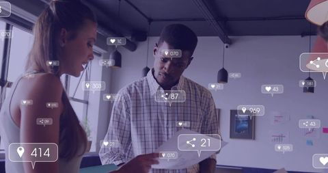 Colleagues reviewing marketing metrics with floating social analytics graphics in office