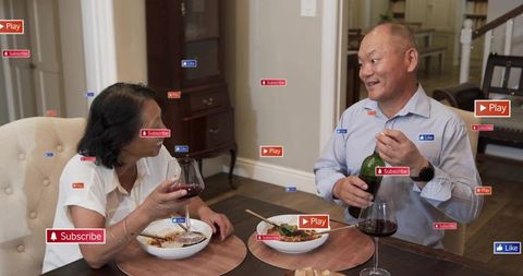 Asian couple sharing dinner and wine at home, man pouring bottle while woman holding glass