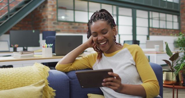 Smiling Woman Using Tablet on Sofa in Modern Creative Office - Download Free Stock Images Pikwizard.com