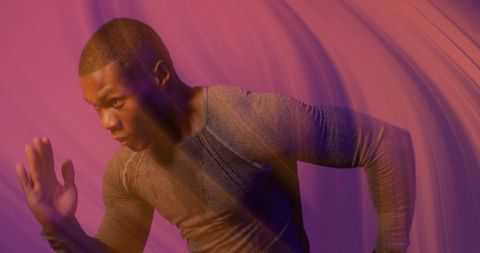 Black male athlete sprinting in studio with magenta light, motion blur and dynamic energy