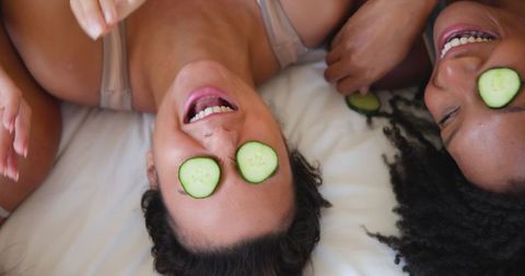 Diverse friends enjoying home spa with cucumber slices on eyes