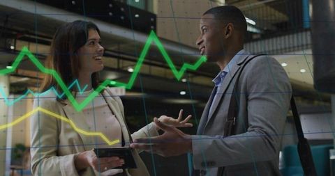 Business professionals discussing finance data with tablet, graph overlay in office atrium
