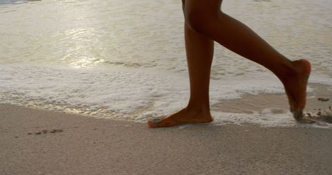 Close-Up of Woman Running on Beach with Waves in Background