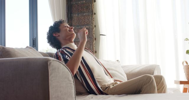 Young Man Relaxing on Couch Laughing Joyfully in Bright Living Room - Download Free Stock Images Pikwizard.com