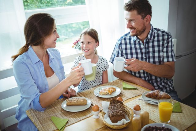 Family toasting a cup of coffee while having breakfast at home