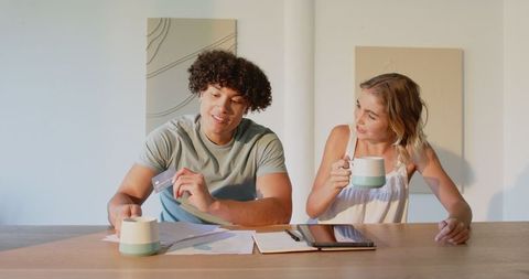 Young couple managing finances with tablet and credit card at home