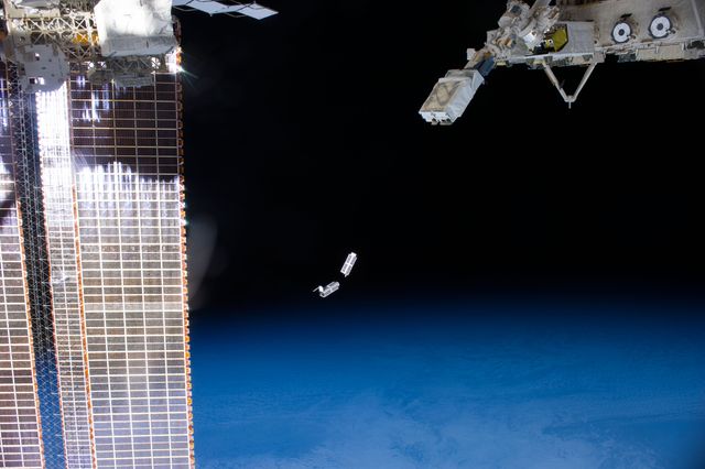 ISS038-E-056324 (25 Feb. 2014) --- A set of NanoRacks CubeSats is photographed by an Expedition 38 crew member after the deployment by the NanoRacks Launcher attached to the end of the Japanese robotic arm. The CubeSats program contains a variety of experiments such as Earth observations and advanced electronics testing. International Space Station solar array panels are at left. Earth's horizon and the blackness of space provide the backdrop for the scene.