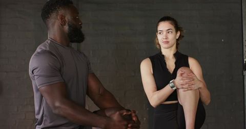 Diverse Friends Performing Knee-to-Chest Stretches in Fitness Studio