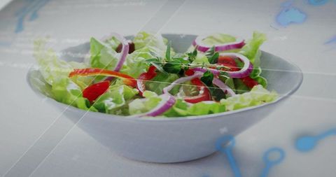 Serving fresh crisp green salad with red onion and bell pepper in white bowl, subtle blue overlay