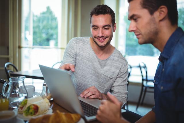 Smiling friends using laptop at cafe table - Download Free Stock Images Pikwizard.com