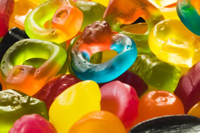 Bright and colorful gummy candies in various shapes and colors. Perfect for use in advertisements for candy brands, articles about sweet treats, or visuals for unhealthy eating habits. The vibrant colors and close-up view make it appealing for marketing materials and social media posts.