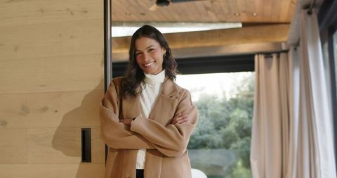 Confident woman leaning on wooden sliding door in modern minimalist living room