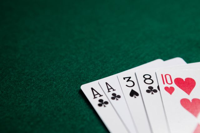 Playing cards arranged on a green poker table, showing a winning hand with aces and hearts. Ideal for use in articles or advertisements related to gambling, casinos, poker strategies, and entertainment. Suitable for illustrating concepts of luck, betting, and leisure activities.