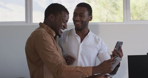 Two Men Collaborating with Smartphone and Documents in Modern Office