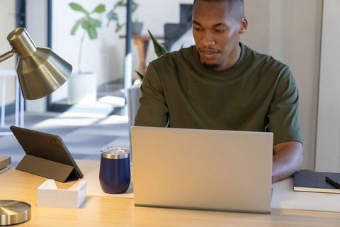 African american man working on laptop in modern minimalist coworking space