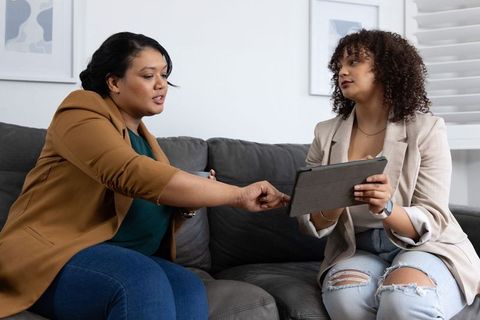 African american women consulting over tablet on sofa during casual business meeting