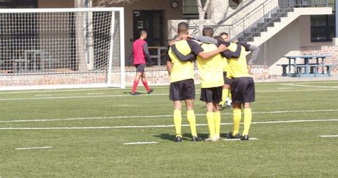 Soccer player preparing penalty kick on sunny field amid team support