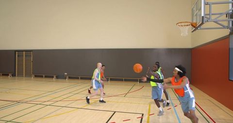 Diverse Male Players Practicing Basketball in Gym