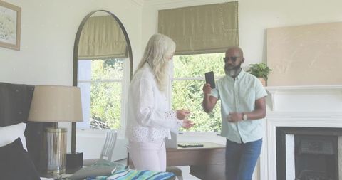 Seniors sharing smartphone moment in bright contemporary living room with fireplace