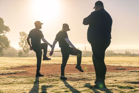 Sunrise team training: coach monitoring players warming up on baseball diamond