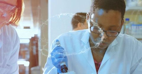 Laboratory Scientist Pipetting at Bench Wearing Gloves and Safety Glasses in Team Research