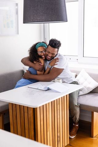 African american couple hugging and laughing in bright modern dining nook
