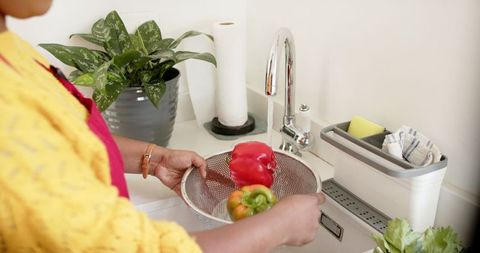 Woman Rinsing Fresh Vegetables at Kitchen Sink