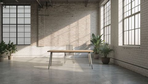 Minimal industrial loft workspace featuring wooden table, metal chair, large windows