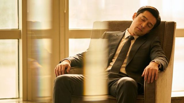 Dozing businessman in dark suit relaxing in armchair by sunlit window