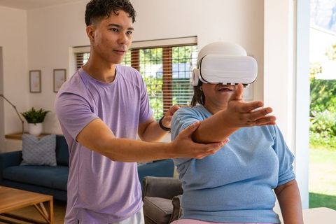 Grandson Assisting Senior Woman with VR Experience in Living Room