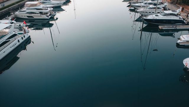 Calm marina reflection showing moored luxury yachts and sailboats