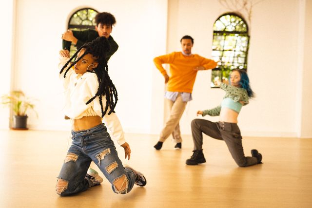 This image showcases a diverse group of young dancers in a spacious studio, practicing contemporary dance moves with energy and coordination. Perfect for use in articles about dance, youth culture, teamwork, and healthy lifestyles. Also suitable for promotional materials for dance schools, fitness classes, and creative workshops.