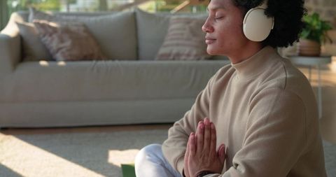 African American Man Meditating and Praying with Headphones in Minimalist Living Room Calm