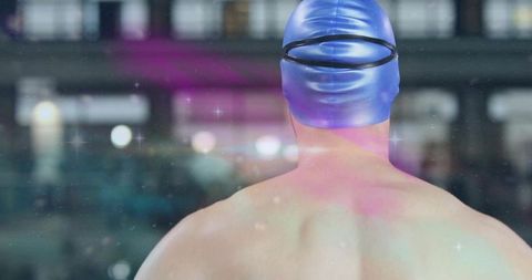 Back view male swimmer wearing blue swim cap preparing for race with dreamy lens flare