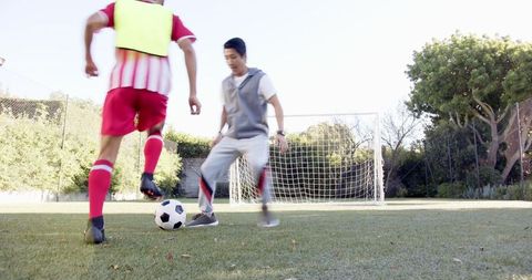 Soccer Training Partners Dribbling on Field Near Goal