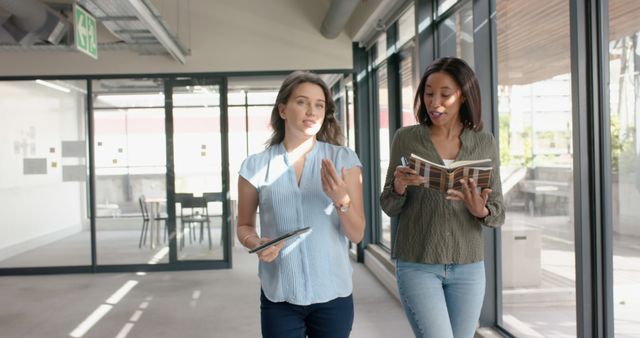 Two Businesswomen Walking and Discussing Documents in Modern Office - Download Free Stock Images Pikwizard.com