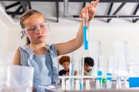Young girl conducting colorful chemistry experiment with test tube in science classroom