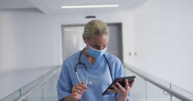 Healthcare Professional Reviewing Patient Data on Digital Tablet in Hospital Hallway - Download Free Stock Images Pikwizard.com