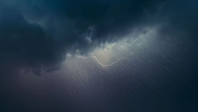 Dramatic lightning bolt striking through dark storm clouds