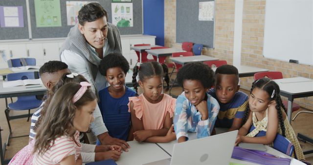 Teacher guiding diverse group of children on laptop in classroom - Download Free Stock Images Pikwizard.com