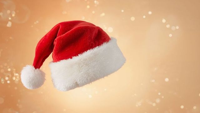 Floating santa hat with plush white faux-fur trim on warm golden bokeh background
