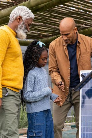 Multigenerational family learning solar panels under pergola teaching renewable energy