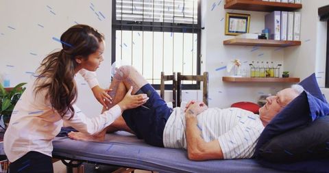 Physiotherapist assessing knee mobility and performing manual therapy for senior rehabilitation