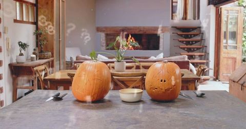Glowing jack-o'-lanterns sitting on kitchen island in rustic home with fireplace