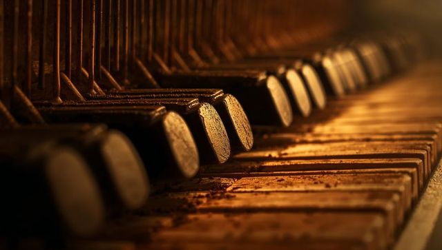 Worn vintage piano keys and felt hammers revealing dust, chipped edges, weathered texture
