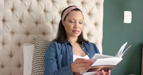 Woman Reading Book on Bed in Cozy Home Setting