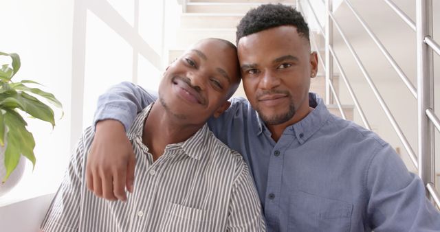 Happy diverse gay male couple embracing at home. Togetherness, relationship, love and domestic life, unaltered.