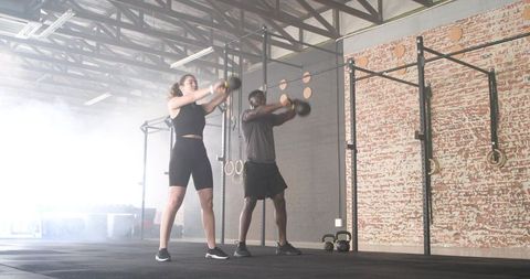 Diverse individuals performing kettlebell workout in modern gym